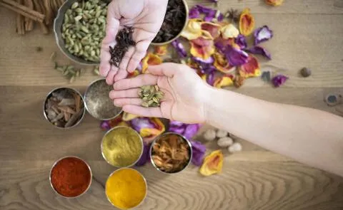 A vibrant top-down shot of a person handling fresh spices and dried botanicals in a holistic kitchen or workshop.