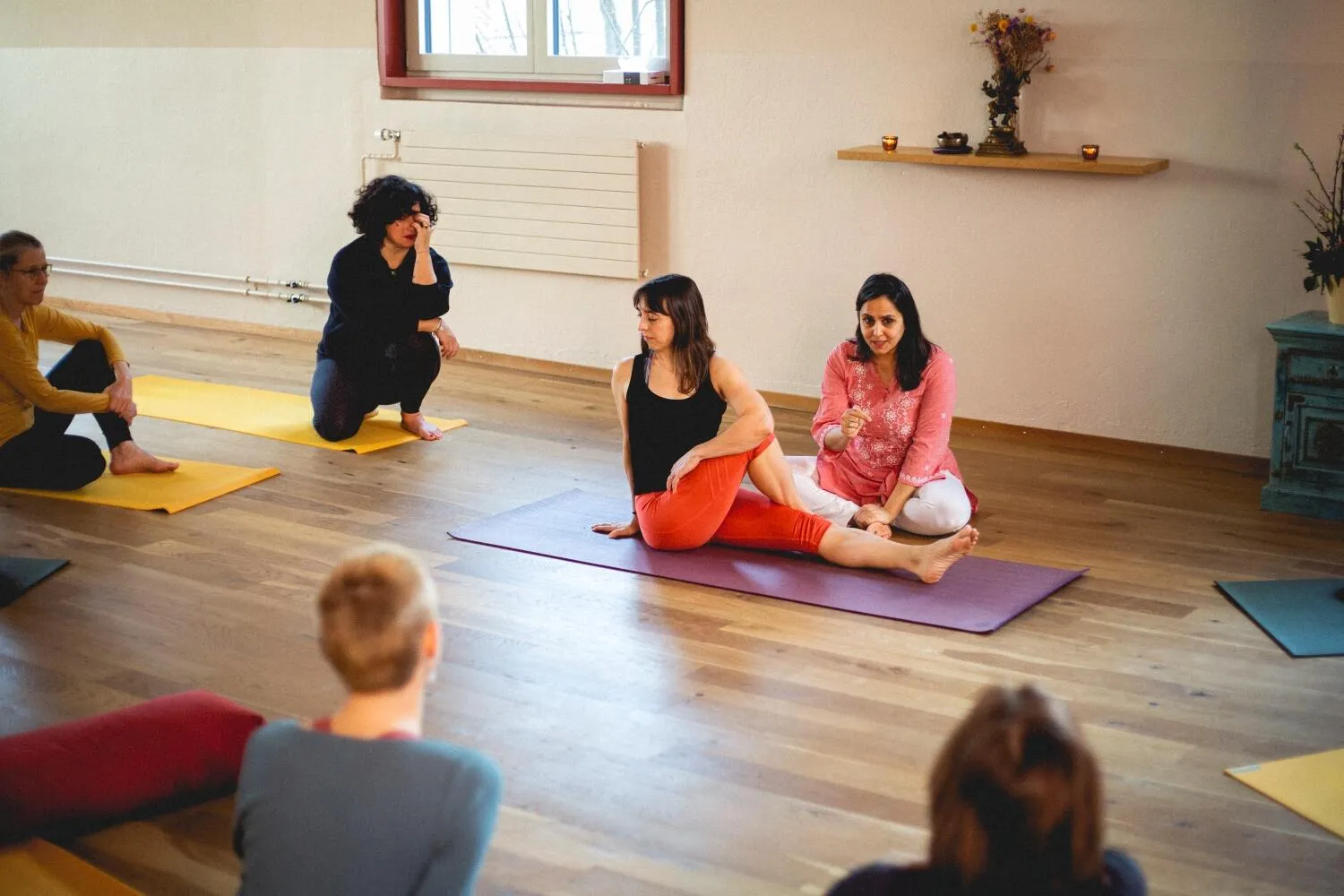 Poonam demonstrates a seated spinal twist yoga pose for a class.